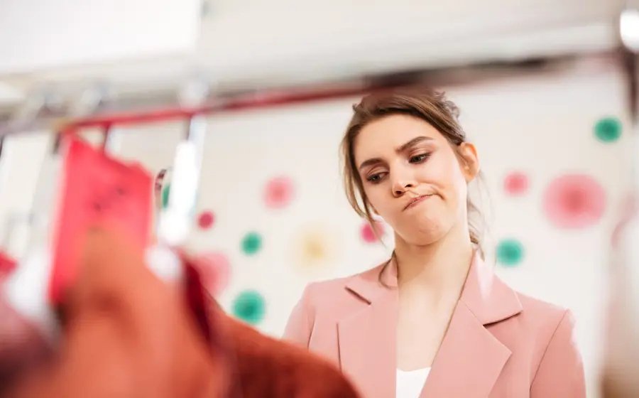 A shopper pausing at a boutique rail, undecided about an item (illustrative photo)